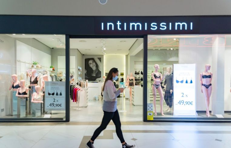 A woman with a mask walking in front of the Intimissimi