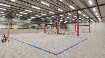 An indoor beach volleyball court with sand and nets.