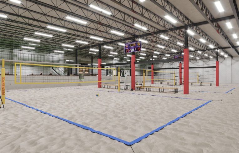 An indoor beach volleyball court with sand and nets.