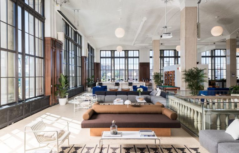 A large open floor plan office space with colorful couches and large windows.