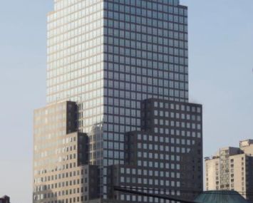 A large grey, boxy skyscraper ascends into a grey sky.