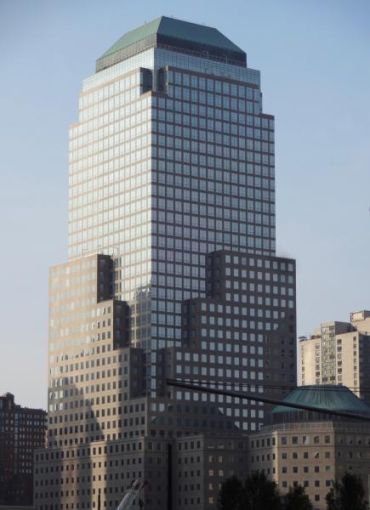 A large grey, boxy skyscraper ascends into a grey sky.