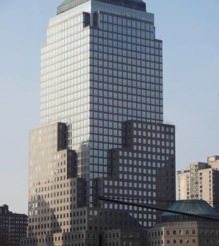 A large grey, boxy skyscraper ascends into a grey sky.