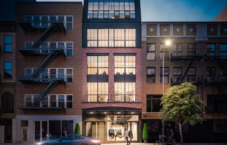 A modern building with large square windows illuminated by a street lamp at night.