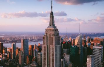 A view of the Empire State Building from the sky as it ascends through clouds.