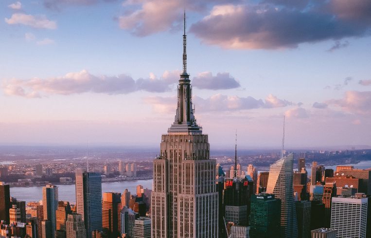A view of the Empire State Building from the sky as it ascends through clouds.