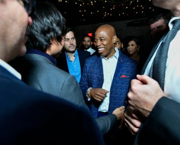 A man in the center of a small crowd, smiling.