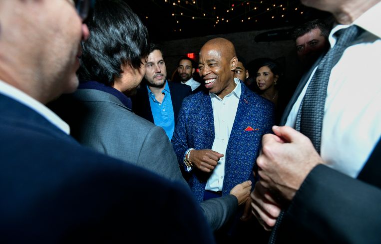 A man in the center of a small crowd, smiling.