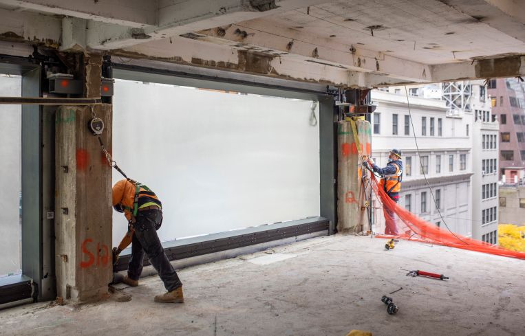 Workers attach a 20-foot by 10-foot piece of glass facade to the building's exterior. Brookfield claims the windows are some of the biggest ever used on a skyscraper.