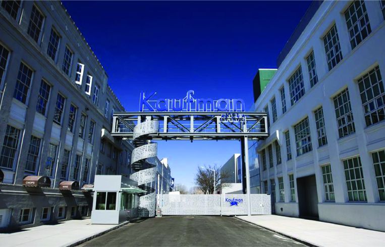 A large studio lot with a sign at the center and two buildings flanking the sign.