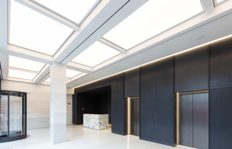 Hand-troweled plaster paneling on the walls contrasts with black metal panels around the elevators in the building's lobby.
