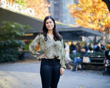 A woman standing before a building in a park.