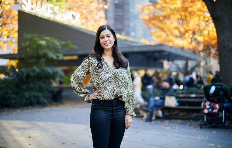 A woman standing before a building in a park.