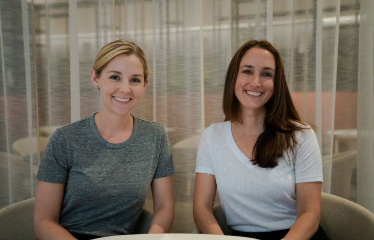 Two women sitting and smiling.