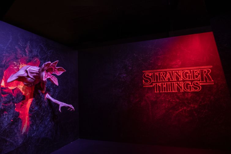The words "Stranger Things" lighted in red with a monster protruding from the wall.