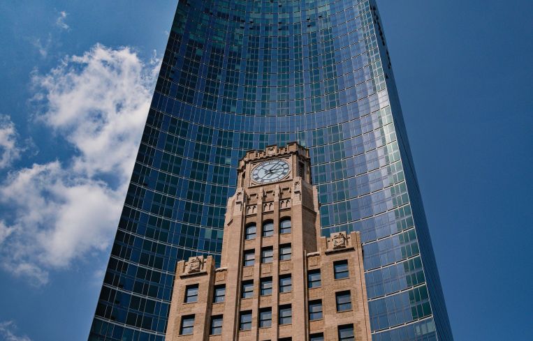 A tall tower with a clocktower in front of it.
