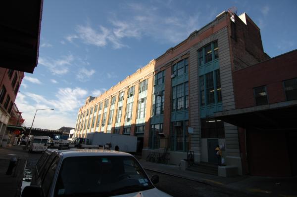A large orange brick building with green windows and a fence in front of it.