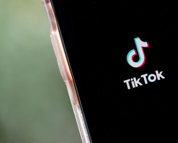 The TikTok app is displayed on an Apple iPhone.