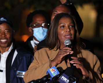Letitia James stands with a microphone in her hands at a podium.