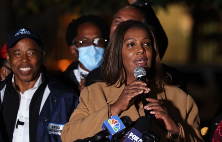 Letitia James stands with a microphone in her hands at a podium.