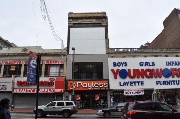 The short building at 162-11 Jamaica Avenue, pictured with a Payless and clothing store.