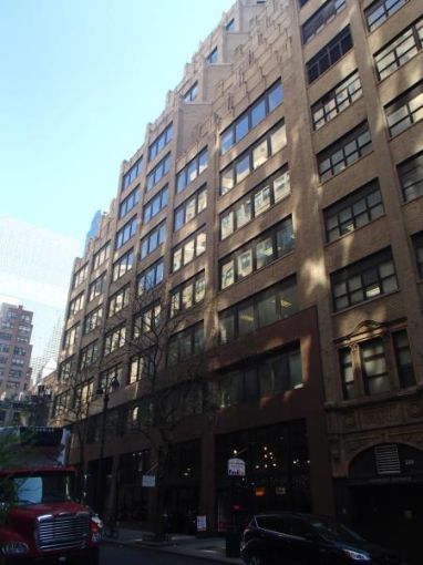 The large brown office building at 228 East 45th Street, from the perspective of one on the street below, with large rectangular windows.