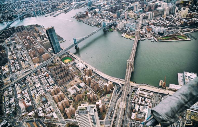 New York City from helicopter point of view. Brooklyn, Manhattan and Williamsburg Bridges with Manhattan skyscrapers on a cloudy day.