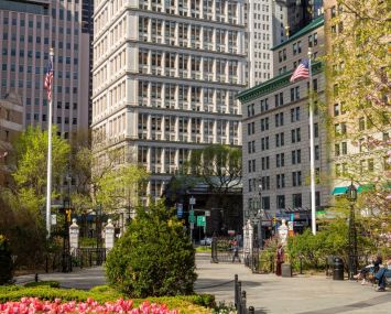 The tall concrete building in the Financial District at 195 Broadway, as seen with a garden of flowers in front of it.