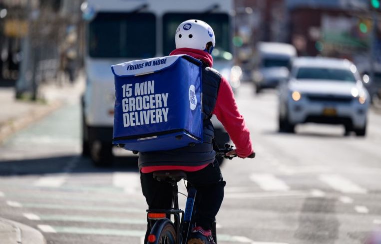 An employee rides a bike to deliver groceries from 'Fridge No More' on March 31, 2021 in the Brooklyn borough of New York City.