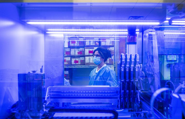 Lisa Bates, a medical technologist is seen through the window of a PCR analysis machine in the PCR testing lab at Quest Diagnostics in February 2022 in Indianapolis, Indiana. The lab is capable of processing up to 3700 tests per day.