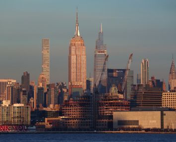 Cranes stand above a new Google office building being constructed in Tribeca in front of the Empire State Building as seen from Jersey City. New York totaled $49 billion of commercial investment in 2021.