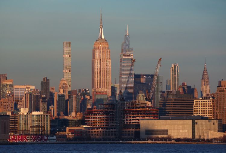 Cranes stand above a new Google office building being constructed in Tribeca in front of the Empire State Building as seen from Jersey City. New York totaled $49 billion of commercial investment in 2021.