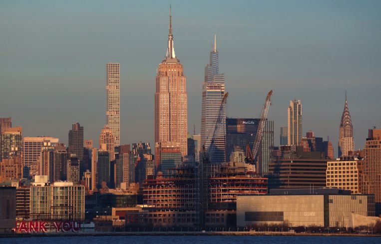 Cranes stand above a new Google office building being constructed in Tribeca in front of the Empire State Building as seen from Jersey City. New York totaled $49 billion of commercial investment in 2021.
