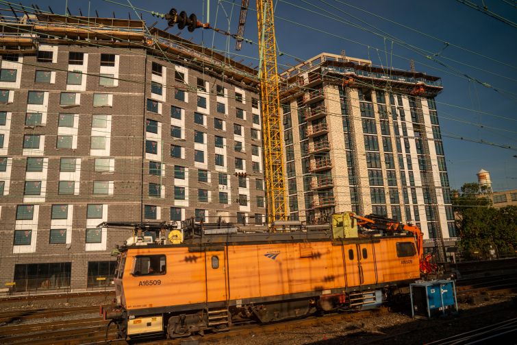 An electric train engine travels past a residential apartment building under construction in October 2021 in Washington, D.C. Real estate demand in the D.C. area has increased over the past two years.
