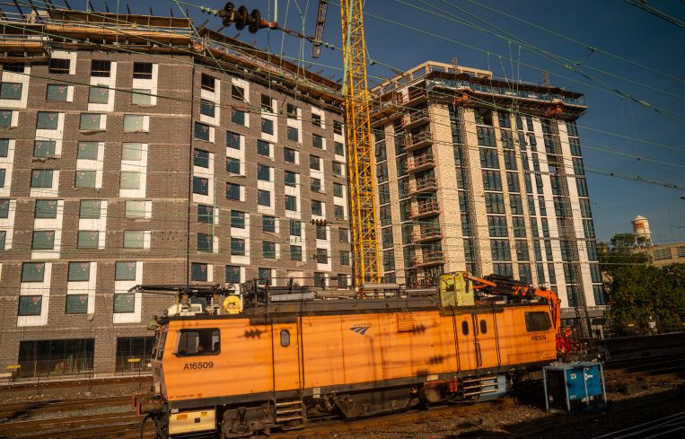 An electric train engine travels past a residential apartment building under construction in October 2021 in Washington, D.C. Real estate demand in the D.C. area has increased over the past two years.