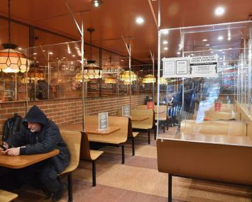 A lone man sits in a hoodie among other people dine at a pizza joint on Feb. 12, 2021 in New York City.