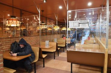 A lone man sits in a hoodie among other people dine at a pizza joint on Feb. 12, 2021 in New York City.