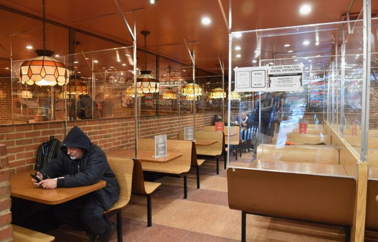 A lone man sits in a hoodie among other people dine at a pizza joint on Feb. 12, 2021 in New York City.
