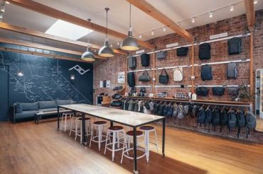 The inside of a Peak Design store, with exposed brick walls covered in bags.