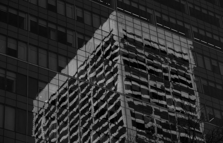 An office building is reflected in the windows of another with lights off in New York.