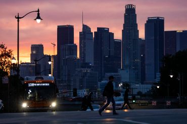 A glowing sky provides a colorful backdrop to the Downtown Los Angeles skyline, seen from Boyle Heights on March 15, 2022.