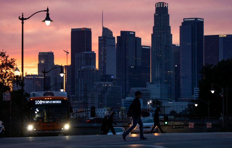 A glowing sky provides a colorful backdrop to the Downtown Los Angeles skyline, seen from Boyle Heights on March 15, 2022.