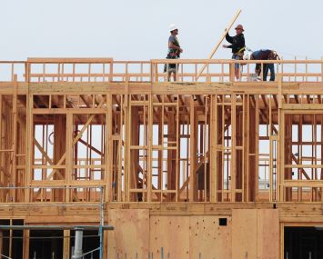 Construction workers are seen atop a building of new apartments for sale east of Downtown Los Angeles.