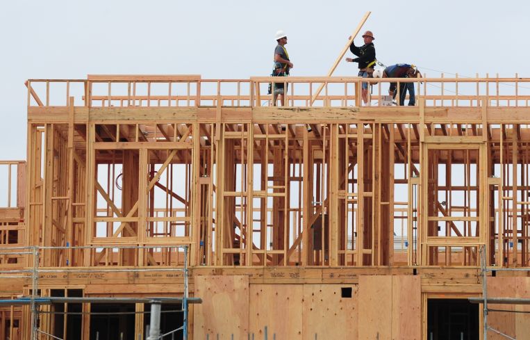 Construction workers are seen atop a building of new apartments for sale east of Downtown Los Angeles.