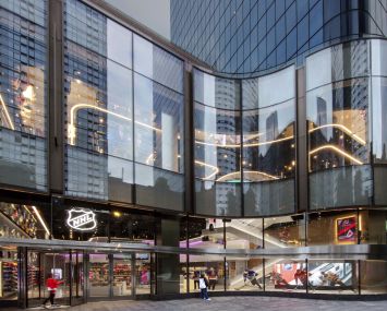 The new NHL shop, designed by TPG Architecture, tries to reference both the undulating facade of One Manhattan West and the feel and shape of a hockey rink.