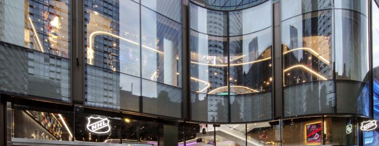 The new NHL shop, designed by TPG Architecture, tries to reference both the undulating facade of One Manhattan West and the feel and shape of a hockey rink.