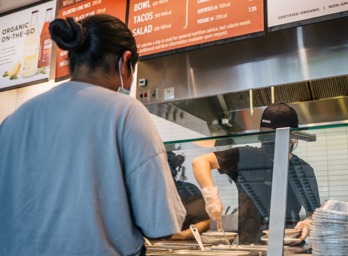 A woman waits in line for food at a Chipotle Mexican Grill.