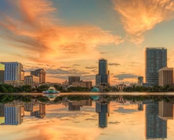 A colorful sunset over Lake Eola and Orlando, Florida with reflections captured off the lake.