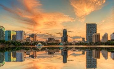 A colorful sunset over Lake Eola and Orlando, Florida with reflections captured off the lake.