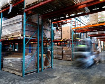 Workers on forklifts move inventory.